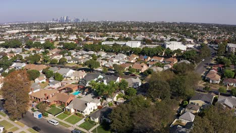 Aerial-descending-shot-of-a-South-LA-neighborhood-with-Downtown-Los-Angeles-in-the-background