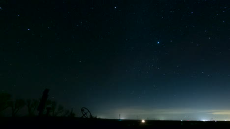 The-silhouette-of-rusted-tractor-marks-the-horizon-as-the-heavenly-stars-cross-the-night-sky---time-lapse