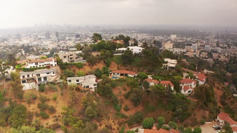Aerial-wide-shot-of-homes-in-the-Hollywood-Hills-with-hazy-Los-Angeles-in-the-background
