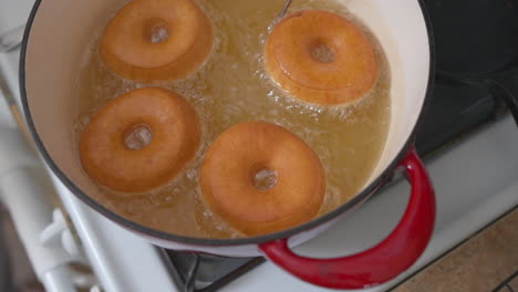 Homemade-donuts-frying-in-hot-oil-in-a-Dutch-oven-on-the-stove-top---slow-motion-sizzle