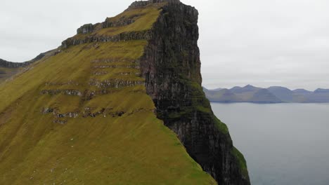 Beautiful-aerial-parallax-of-incredible-tall-cliff-in-the-ocean-in-the-landscape-of-the-Faroe-Islands-on-a-cloudy-day