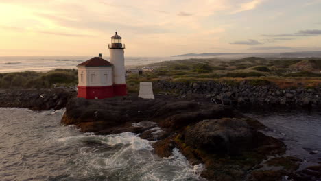Coquille-River-Lighthouse-Against-Sunset-Sky-With-Splashing-Waves-On-Rocky-Shoreline-In-Bandon,-Oregon