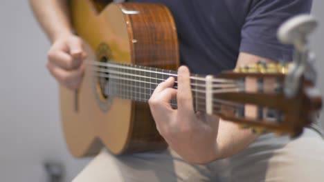 A-professional-guitarist-playing-on-an-acoustic-guitar-during-a-redording-session-in-a-studio-with-racking-focus