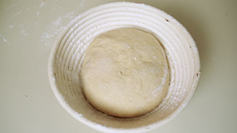 Top-view-of-a-baker-placing-the-dough-into-a-round-banneton-proofing-basket