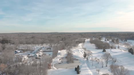Level-drone-view-of-a-snowy-golf-course-abutting-a-neighborhood-and-a-cemetery