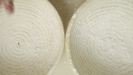 Top-view-of-a-baker-dusting-two-proofing-baskets-with-some-organic-flour