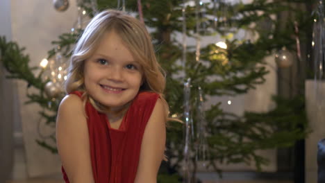 Niña-Rubia-Feliz-Sonríe-Con-árbol-De-Navidad-Detrás-De-Ella