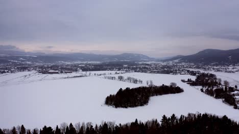 Aerial-shot-of-an-agricultural-field-near-a-small-village-in-winter-in-Quebec