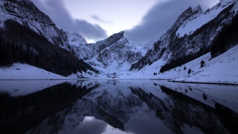 Winter-twilight-time-lapse-of-lake-Seealpsee-in-Appenzell,-Switzerland-during-winter-with-snow-and-reflection