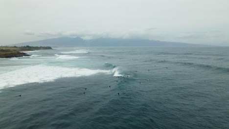 Vista-Aérea-De-Un-Grupo-De-Surfistas-Montando-Olas-En-La-Playa-De-Paia,-Maui,-Hawaii