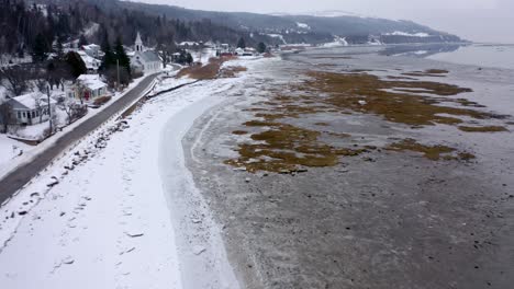 Drone-view-of-a-small-village-on-the-shore-of-the-Saint-Lawrence-river-in-wintertime