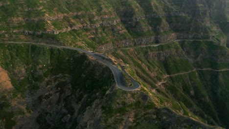 Sharp-turn-in-mountainous-road-on-green-rocky-slope-of-Madeira-range