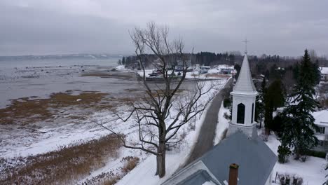 Drone-flying-near-a-church-on-the-edge-of-the-Saint-Lawrence-River-in-wintertime
