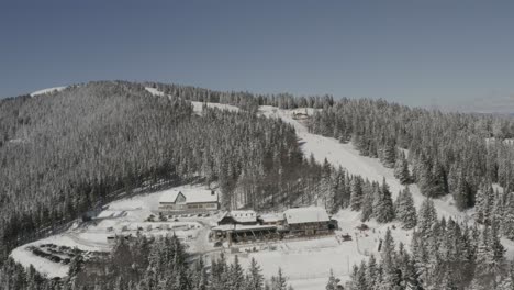 Kope-Winter-Resort-In-Slowenien-Im-Pohorje-gebirge-Mit-Skifahrern,-Die-Bei-Ribnica-Eine-Spur-Bergab-Fahren,-Luftschwenk-Rechtsaufnahme
