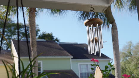 Calming-and-relaxing-view-from-a-garden-with-wind-chimes-during-summer-with-palm-trees-and-cute-houses-in-tropical-Florida