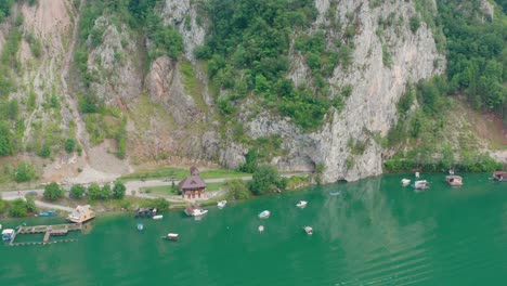 Aerial-View-of-House-and-Boats-on-Perucac-Lake-Lakeside,-Serbia,-Green-Water-and-Steep-Cliff,-Popular-Recreational-Area,-Drone-Shot