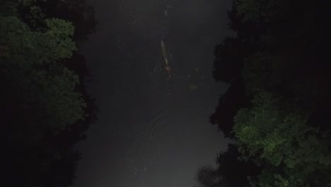 Aerial-view-of-an-indigenous-person-paddling-a-canoe-in-a-rainforest-river