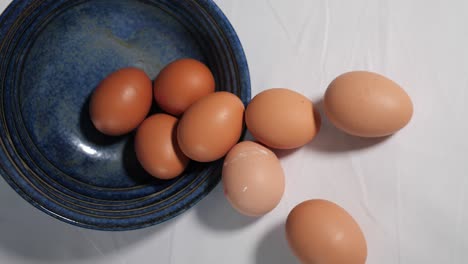 Huevos-De-Gallina-Derramándose-De-Un-Tazón-Azul---Quizás-Ingredientes-Para-Hornear