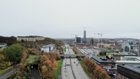 Traffic-At-E6-European-Route-In-Gothenburg,-Sweden-With-Train-Moving-On-The-Railway