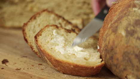 Baker-spreading-some-butter-on-a-crusty-sourdough-bread