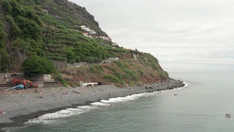 Hidden-beach-with-grey-pebbles-on-volcanic-island-Madeira,-aerial