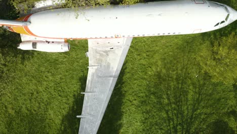 Top-Down-Aerial-View-of-Abandoned-Airplane-in-Green-Field-on-Windy-Day