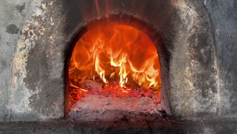Stone-oven-with-logs-on-fire,-flames-getting-out-of-the-oven