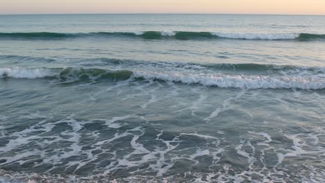 Gentle-sea-waves-lap-near-the-shore-of-the-sea-at-sunset
