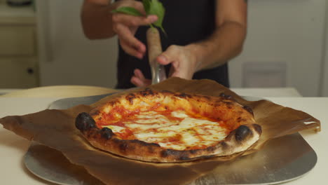 Pizzaiolo-Sirviendo-La-Pizza-Margherita-Napolitana-Más-Increíble-Y-Terminándola-Con-Un-Poco-De-Albahaca-Fresca