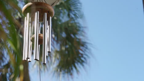 Calming-and-relaxing-view-of-a-wind-chime-with-some-palm-trees-in-the-background,-in-a-nice,-tropical-and-summery-scene-in-Florida