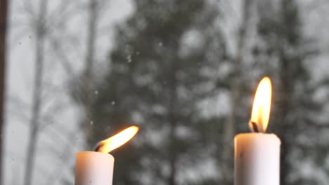 Rack-Focus-Of-winter-snow-falling-to-lit-candles-in-window