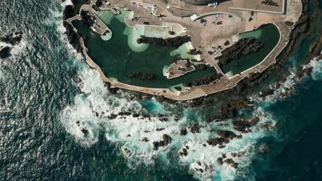 Famous-natural-swimming-pools-on-volcanic-rocky-shore-of-Madeira,-aerial