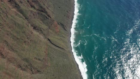 Steep-sloped-shoreline-at-Madeira-with-vivid-blue-ocean-water,-aerial