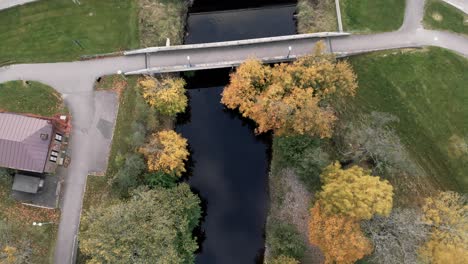 Luftaufnahme-Eines-Flusses,-Umgeben-Von-Wunderschönen-Bunten-Herbstbäumen-über-Einer-Autobahn