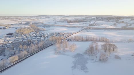 Winterlandschaft-Mit-Einem-Dorf-Mit-Großen-Häusern-Und-Mit-Weißem-Schnee-Bedeckten-Feldern-An-Einem-Hellen,-Kalten-Tag-In-Schottland-Während-Der-Goldenen-Stunde