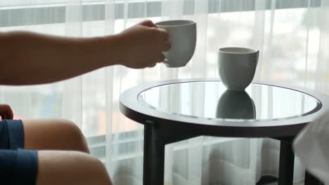 Hand-grabbing-a-cup-of-tea-or-coffee-from-the-table