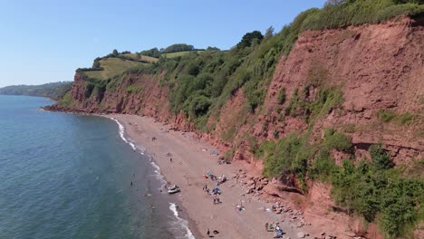 Aerial-drone-side-shot-of-ness-cove-beach-with-many-tourists-relaxing-during-beautiful-summertime
