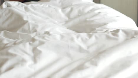 View-of-feet-moving-under-blanket-on-white-bed