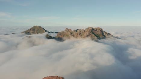 Sea-of-clouds-surrounding-tall-mountain-peaks-of-Madeira-Island,-aerial