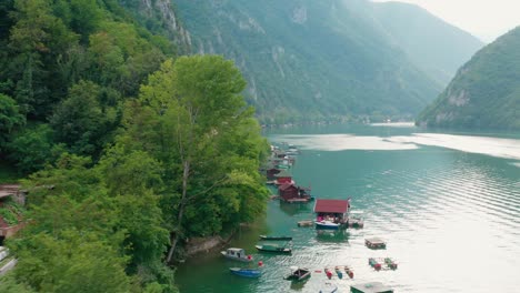 Floating-Houses-Of-Perucac-Lake-On-The-Drina-River,-Western-Serbia,-Surrounded-By-A-Valley,-Narrow-Canyon-And-Forest---aerial-drone-shot