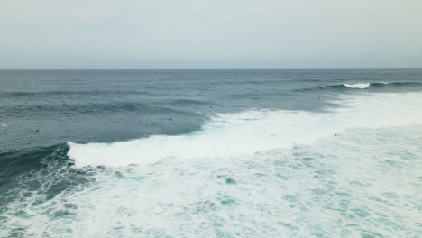 Olas-Del-Océano-Pacífico-Salpicando-Vista-Aérea,-Surfistas-Esperando-Una-Marea