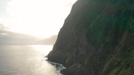 Female-tourist-enjoys-stunning-view-at-steep-cliffs-with-bright-sunrise,-Madeira