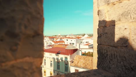 Portugal-Loule-city-through-castle-wall-battlements-under-blue-sky-with-truck-camera-movement-4K