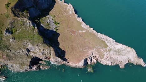 Epic-aerial-top-down-of-overgrown-rocky-ocean-shore-and-bay-along-south-devon-coast,-England