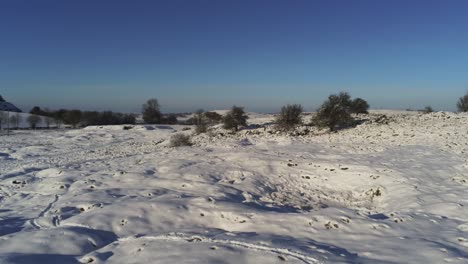 Schneebedeckte-Ländliche-Winterlandschaft-Spur-Fußabdruck-Schatten-Gelände-Luftaufnahme-Niedrige-Vorwärtsbahn-Rechts