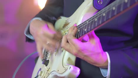 Close-up-of-a-professional-musician-playing-fast-chords-on-an-electric-stratocaster-guitar-during-a-live-session-on-stage-with-warm-studio-lights-in-the-blurred-background