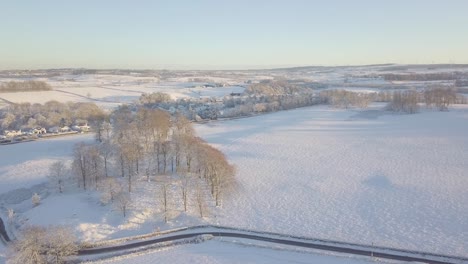 Winter-landscape-with-trees-and-fields-covered-with-white-snow-on-a-bright-cold-day-in-Scotland-during-golden-hour