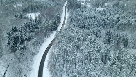 Cars-Traveling-Across-Country-Road-Between-Spruce-Forest-Covered-In-Fresh-Snow-At-Winter-Near-Pieszkowo-Village,-Poland