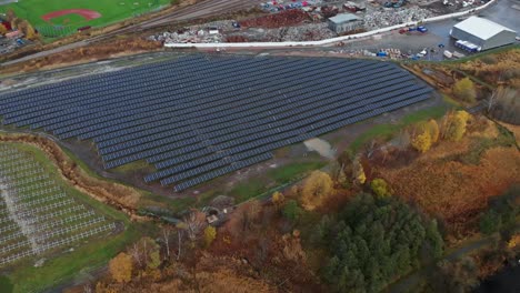 Aerial-view-of-solar-energy-panels-near-a-baseball-field,-pullback