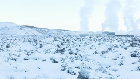Volcanic-landscape-covered-in-white-snow-with-steam-rising-from-power-plant